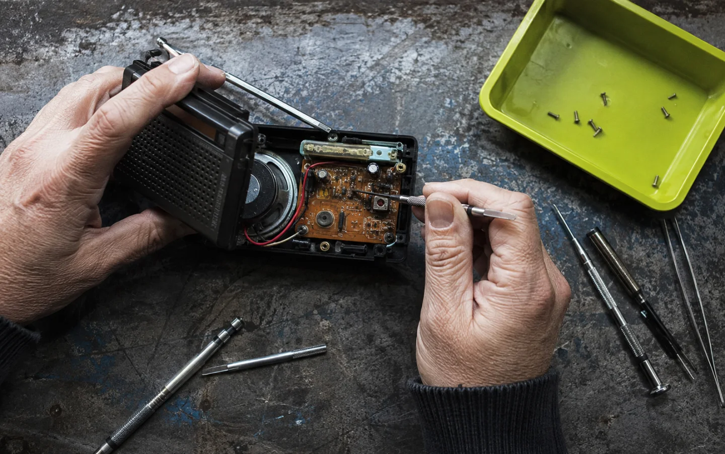Hands repairing a portable radio on a workbench